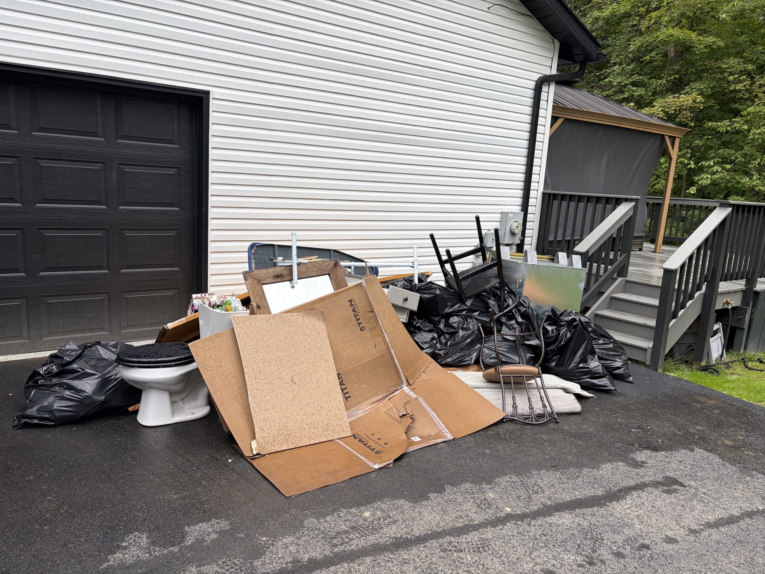 Junk and household items piled in driveway before removal